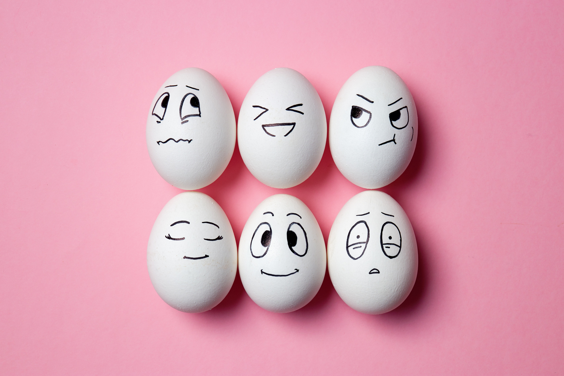 Six white eggs with hand-drawn faces showing different feelings