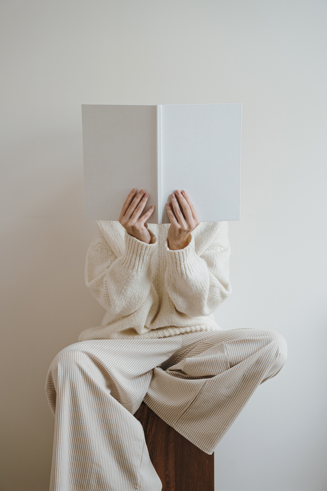 Someone in a cream outfit holding up an open book